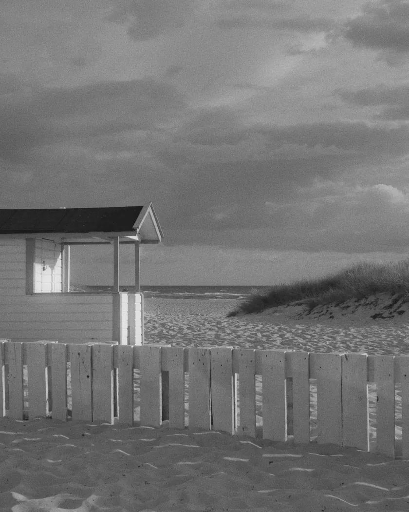 After: beach cabin under storm clouds, with the preset inspired by Foma Retropan 320 Soft (GA — 086 / P) applied (simulation).