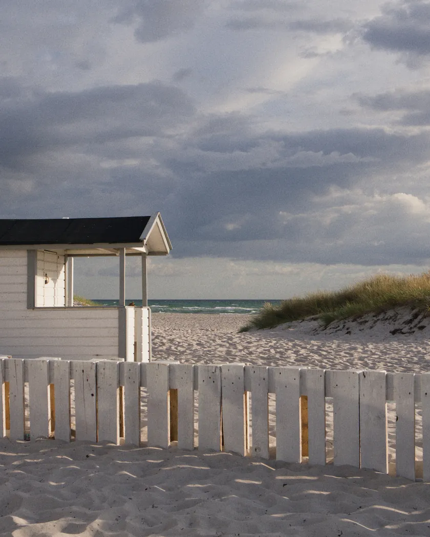 After: beach cabin under storm clouds, with the preset inspired by Fujifilm Superia 800 (GA — 074 / P) applied (simulation).