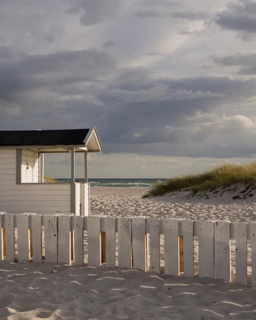 After: beach cabin under storm clouds, with the preset inspired by Kodak Kodachrome 25 (GA — 076 / P) applied (simulation).