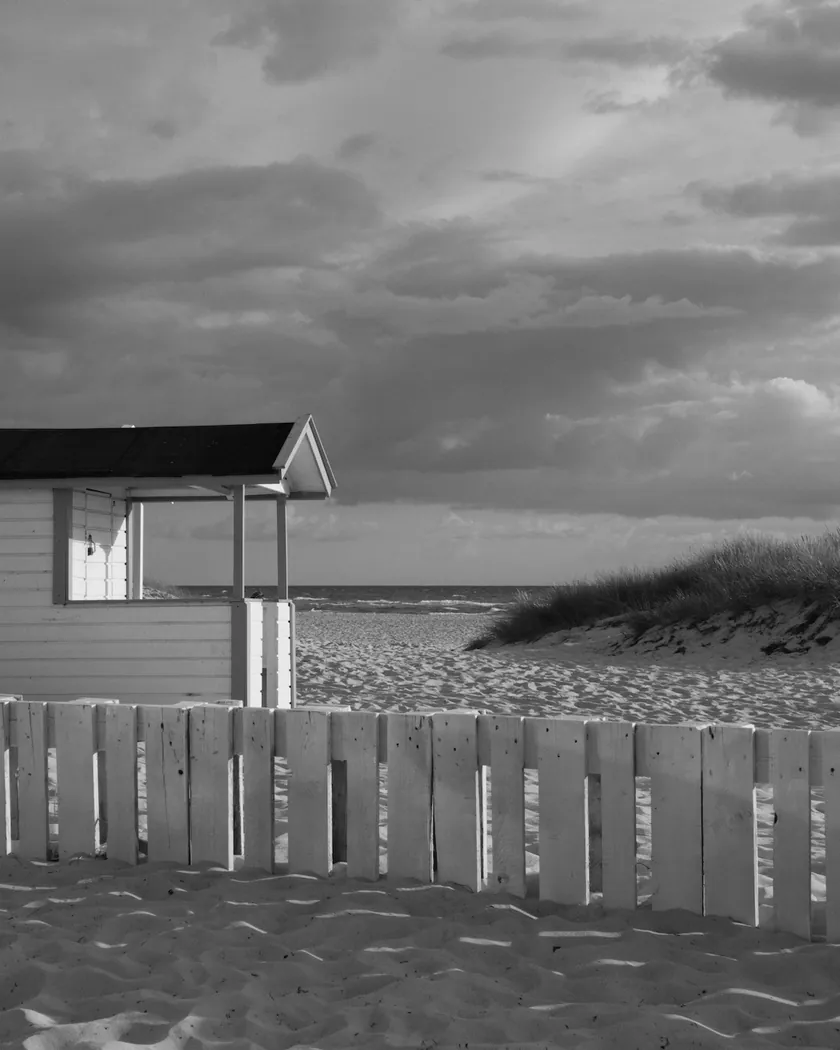 After: beach cabin under storm clouds, with the preset inspired by Kodak Panatomic-X (GA — 084 / P) applied (simulation).