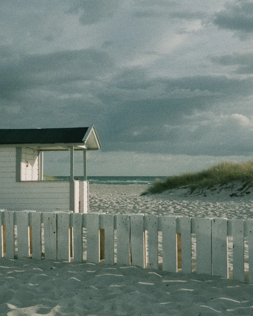After: beach cabin under storm clouds, with the preset inspired by ORWO Wolfen NC400 (GA — 072 / P) applied (simulation).