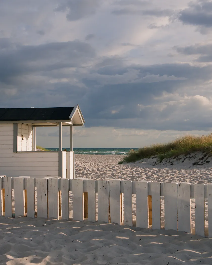 Beach cabin under storm clouds, with the preset inspired by Kodak Ektar 100 (GA — 007 / P) applied (simulation).