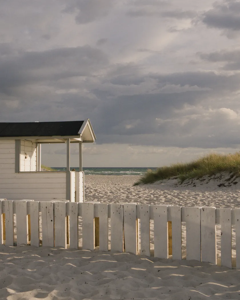 Beach cabin under storm clouds, with the preset inspired by Kodak Portra 400 (GA — 004 / P) applied (simulation).